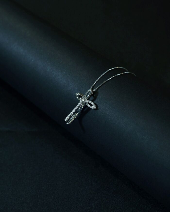 Diamanset Diamond Cross Pendant in white gold, a slender pave-set diamond cross on a fine chain, on a dark studio background